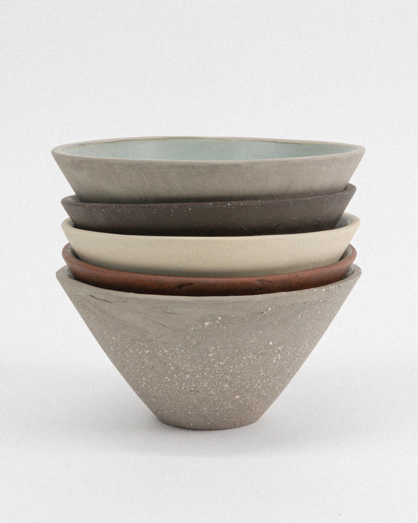 Stack of ceramic bowls in various colors on a white background