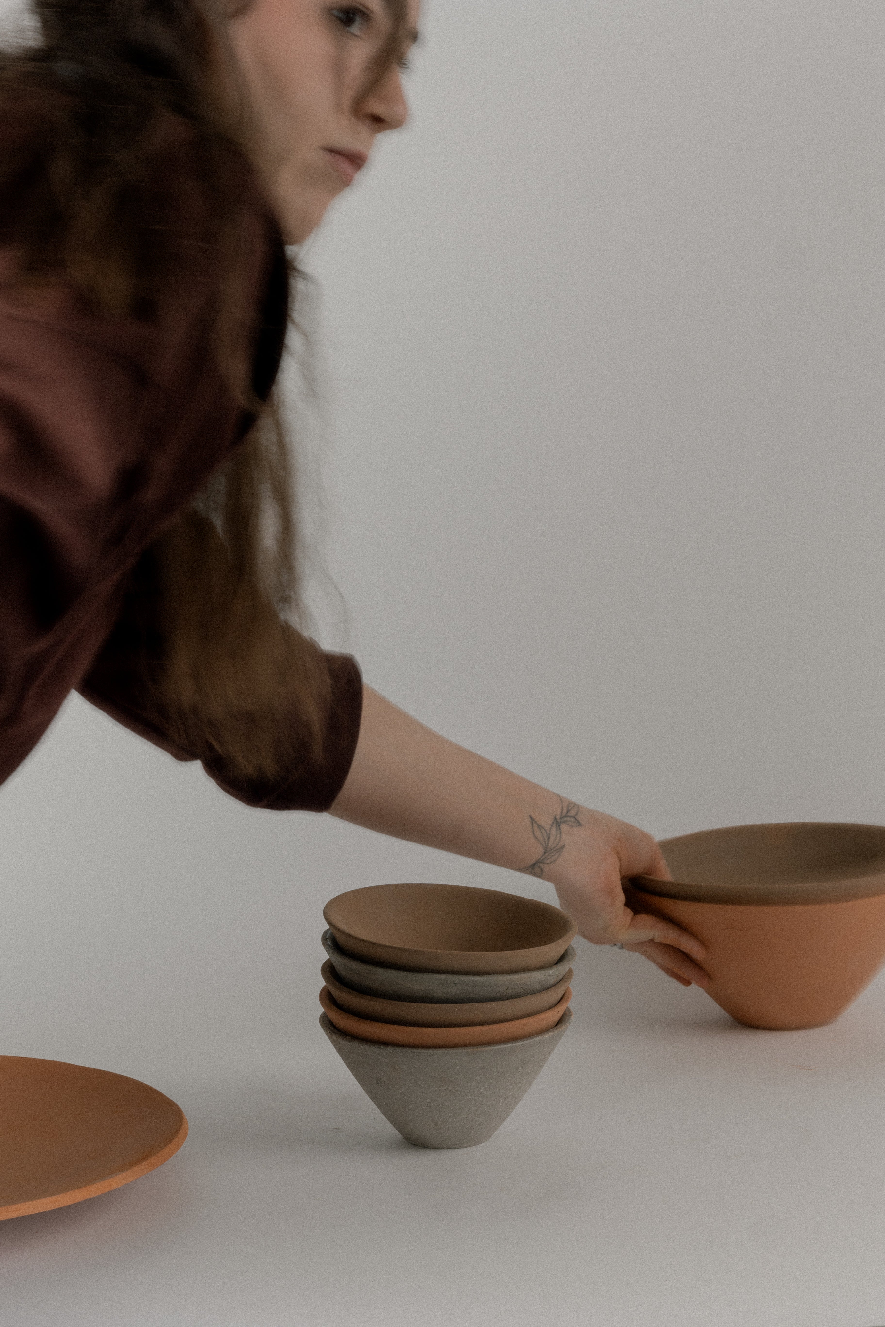 Person arranging ceramic bowls on a white surface