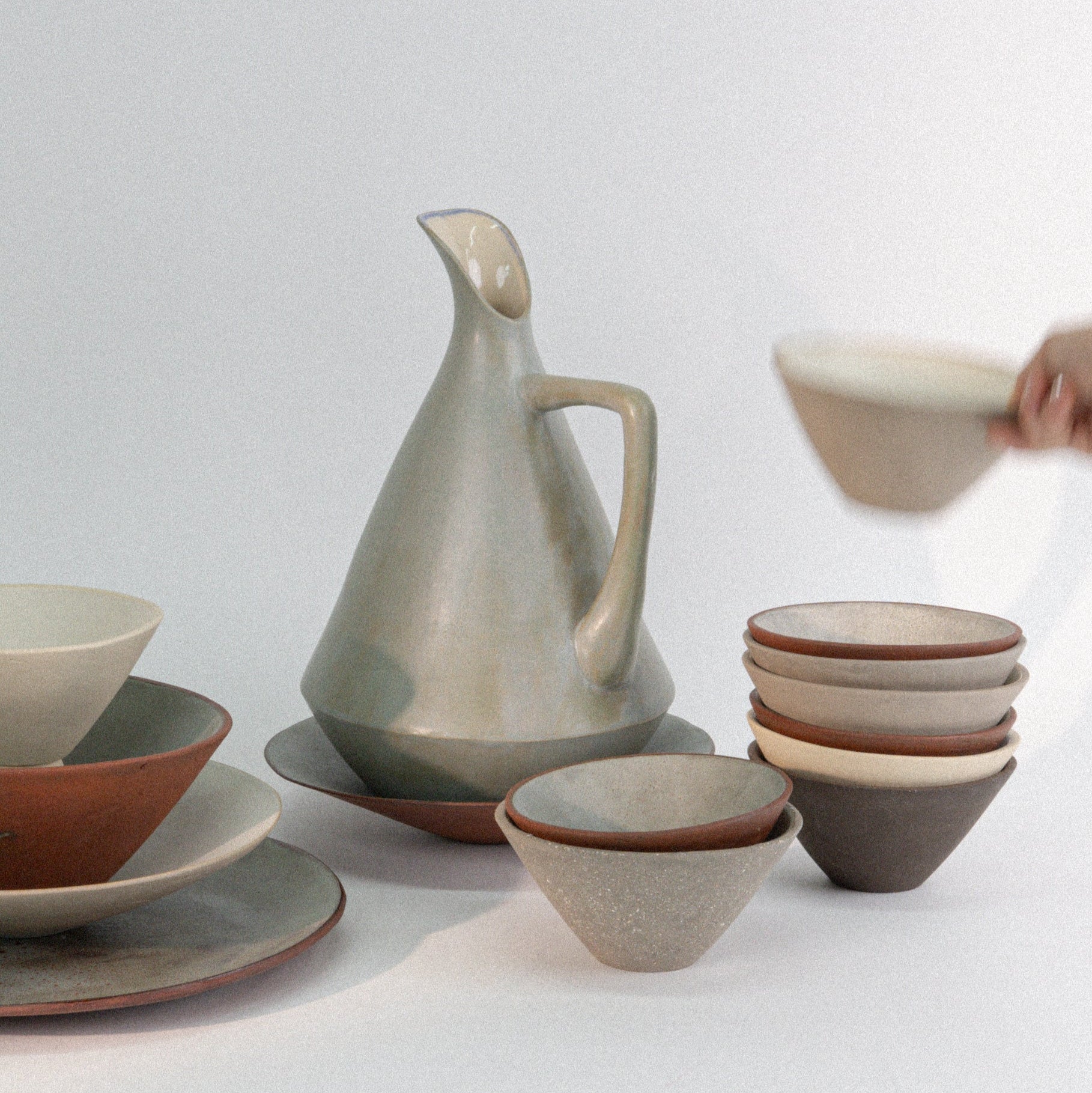 Set of ceramic dishes including bowls and a pitcher on a light background