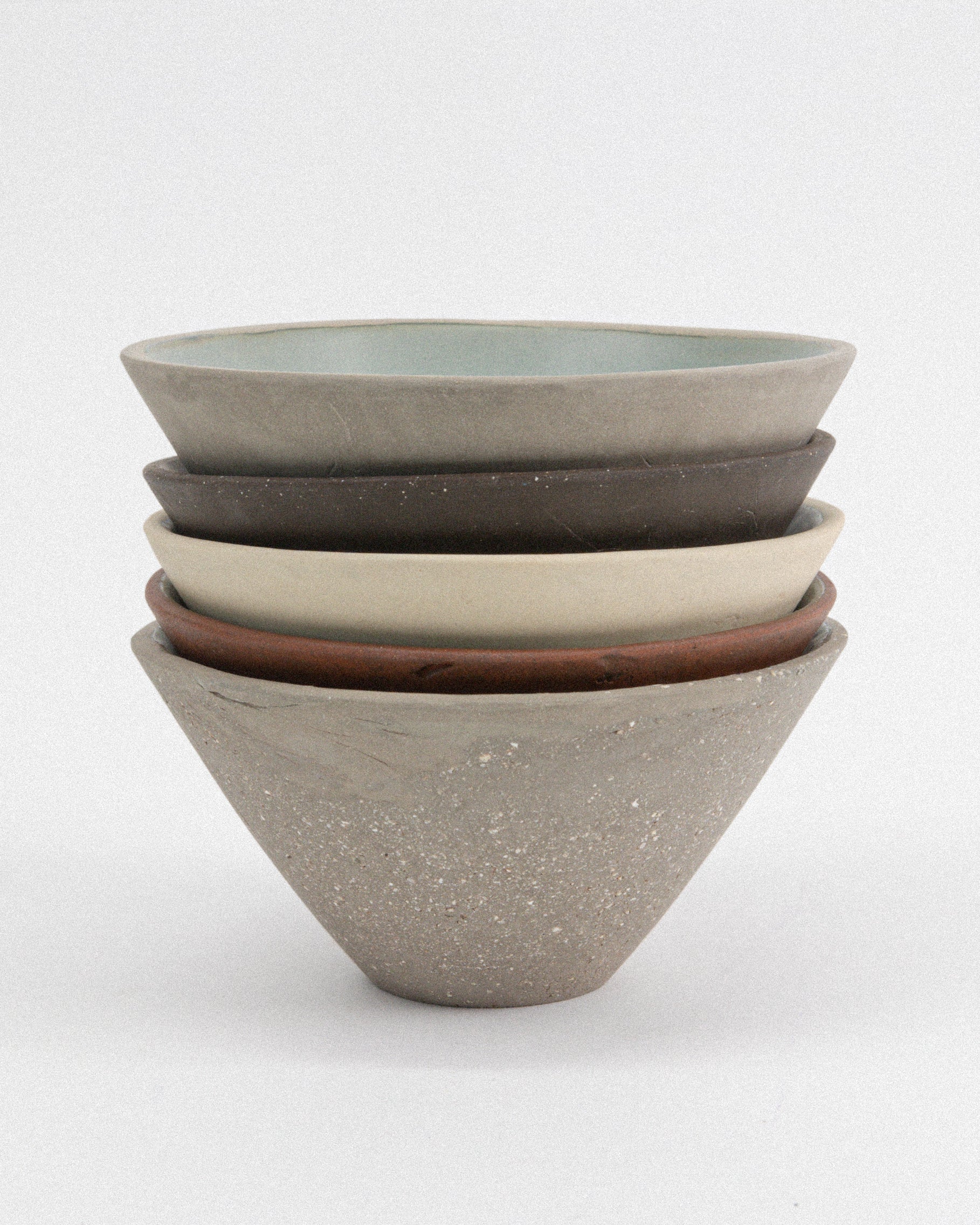Stack of ceramic bowls in various colors on a white background